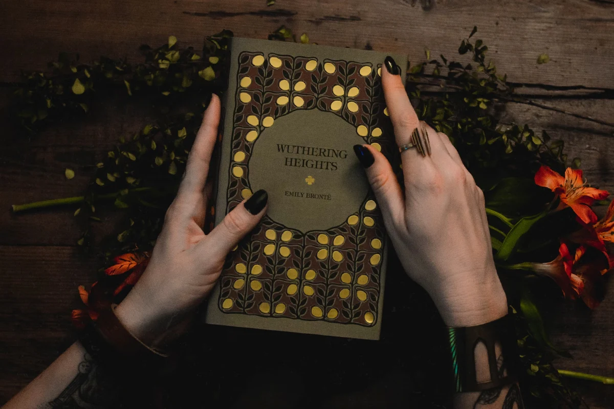 female hands with black manicute holding gothic book