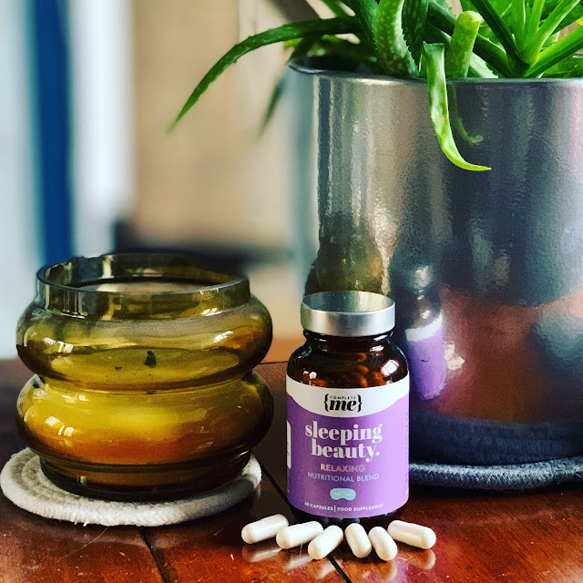 Sleeping Beauty Supplements from Complete Me on table next to Aloe plant and candle in yellow glass