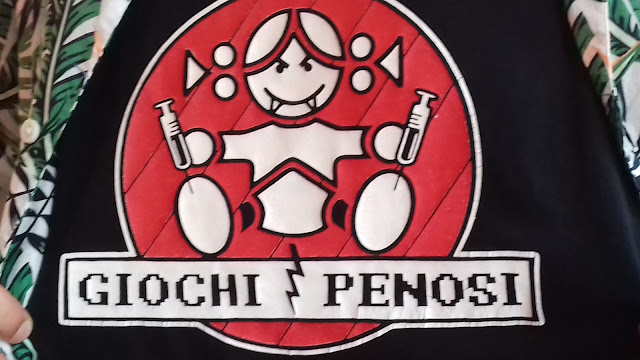 il logo di "giochi penosi" che fa il verso a quello di "giochi preziosi": la bimba si trova su uno sfondo rosso e si inietta due siringhe