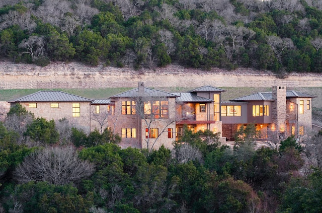 Photo of large modern home as seen from the hill nearby