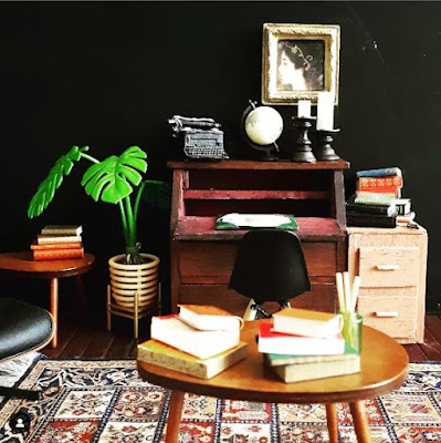 One-twelfth scale modern miniature dark academia study with a writing desk, potted plant, 2-drawer filing cabinet and side tables piled with books.