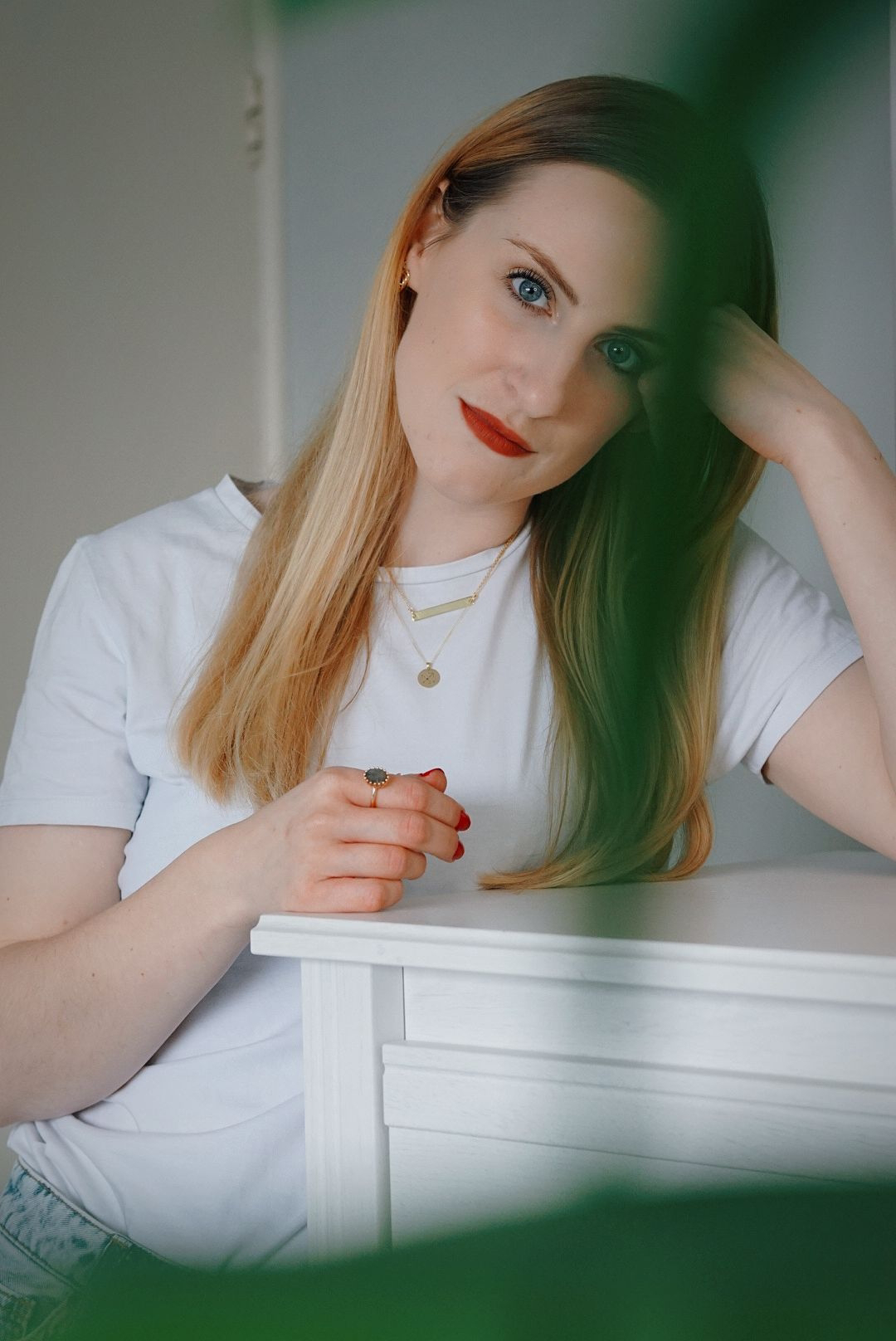 girl in white tee and blue jeans wearing two gold necklaces