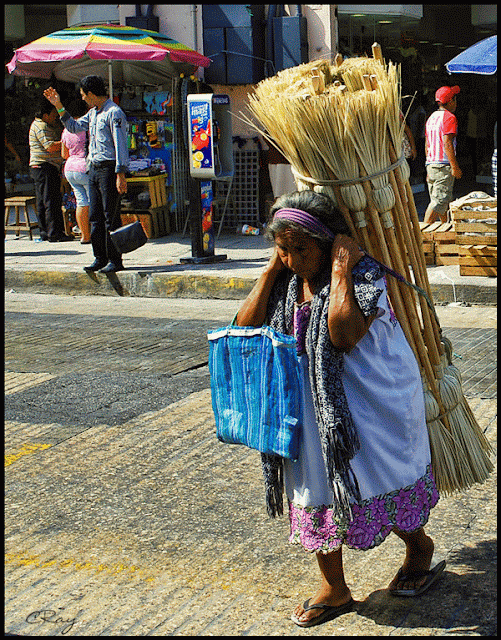 Merida Mexico old woman carrying brooms for sale