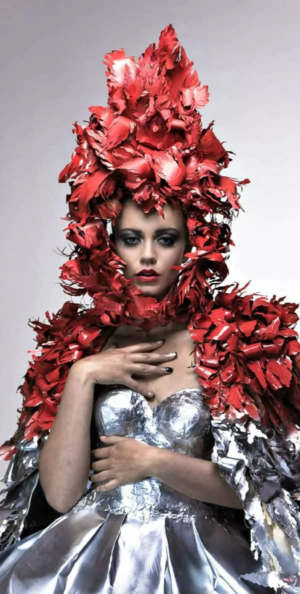 young female model dressed in silver paper dress with red paper flower cape and headpiece