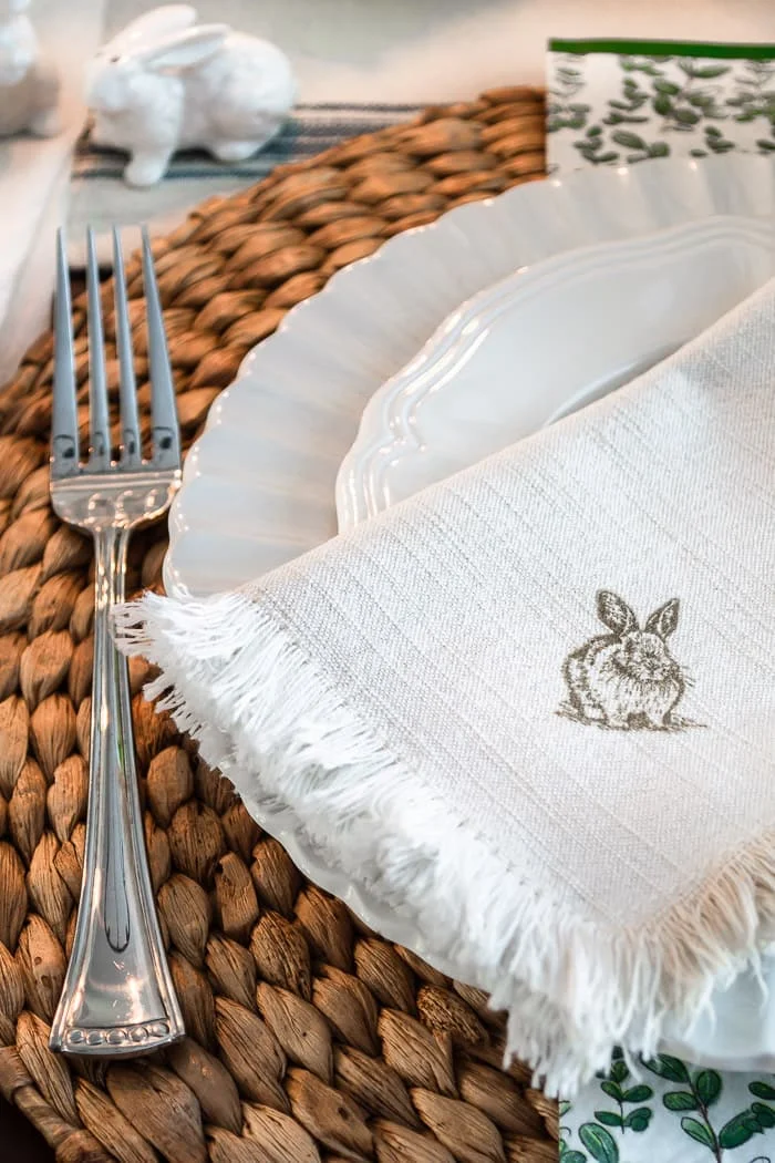close up bunny napkin on white plates, woven charger