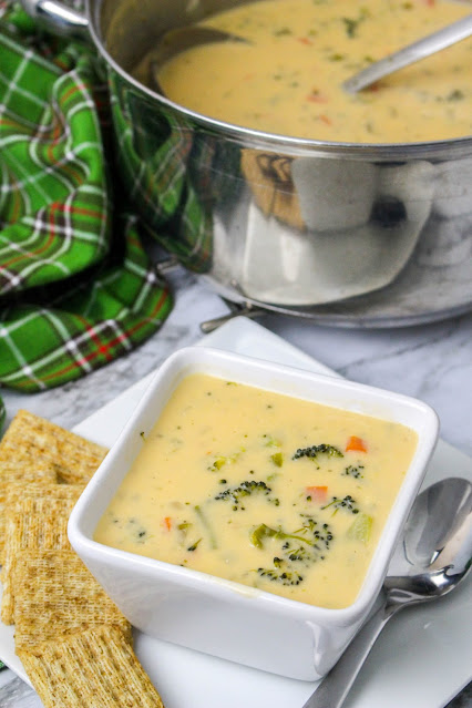 soup in a square white bowl with crackers and a spoon on the side.