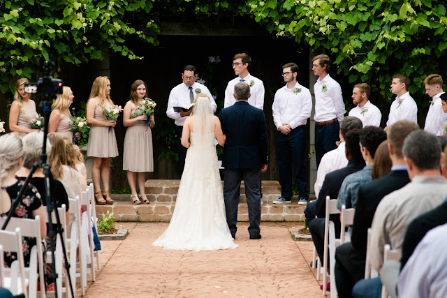 The bride and groom met in college, and have been together for three and a half years.  Maggie said that walking down the aisle towards Jordan was the best part of the day, knowing that they were surrounded by the love and support of friends and family.  She said, “As I walked towards him, Jordan and I were both tearing up and we couldn’t look away from each other.”  Jordan said that since he was “anxious all day, to the point of feeling sick,” the first look was the most memorable part of the day.  He said, “The moment I saw Maggie, I felt 100% relieved, and it made the hours before the ceremony so much more enjoyable.”    The Festivities Event Center in El Reno, OK, was the perfect wedding backdrop, with 10’ windows, a whole second floor to get ready in, and a romantic setting for the outdoor nuptial.  The bride looked “drop-dead gorgeous” in her lace-embroidered, strapless, wedding gown, followed by her bridesmaids, dressed in individually designed gowns in soft hues of dusty rose.  Each bridesmaid had a spring floral bouquet, similar to the bride’s bouquet of pastel pink roses and lilies.    After the couple exchanged wedding vows, pictures of the family and wedding party were taken, and it was time to celebrate!  First dances came next, then guests were invited to enjoy a Mexican buffet.  Dessert included the gorgeous wedding cake, chocolate groom’s cake, and assorted, homemade cookies and pastries.  The evening came to a close as the guests sent the star-gazed couple off with sparklers!  The newly married couple escaped to Cozumel and Yucatan Progreso for their honeymoon.  