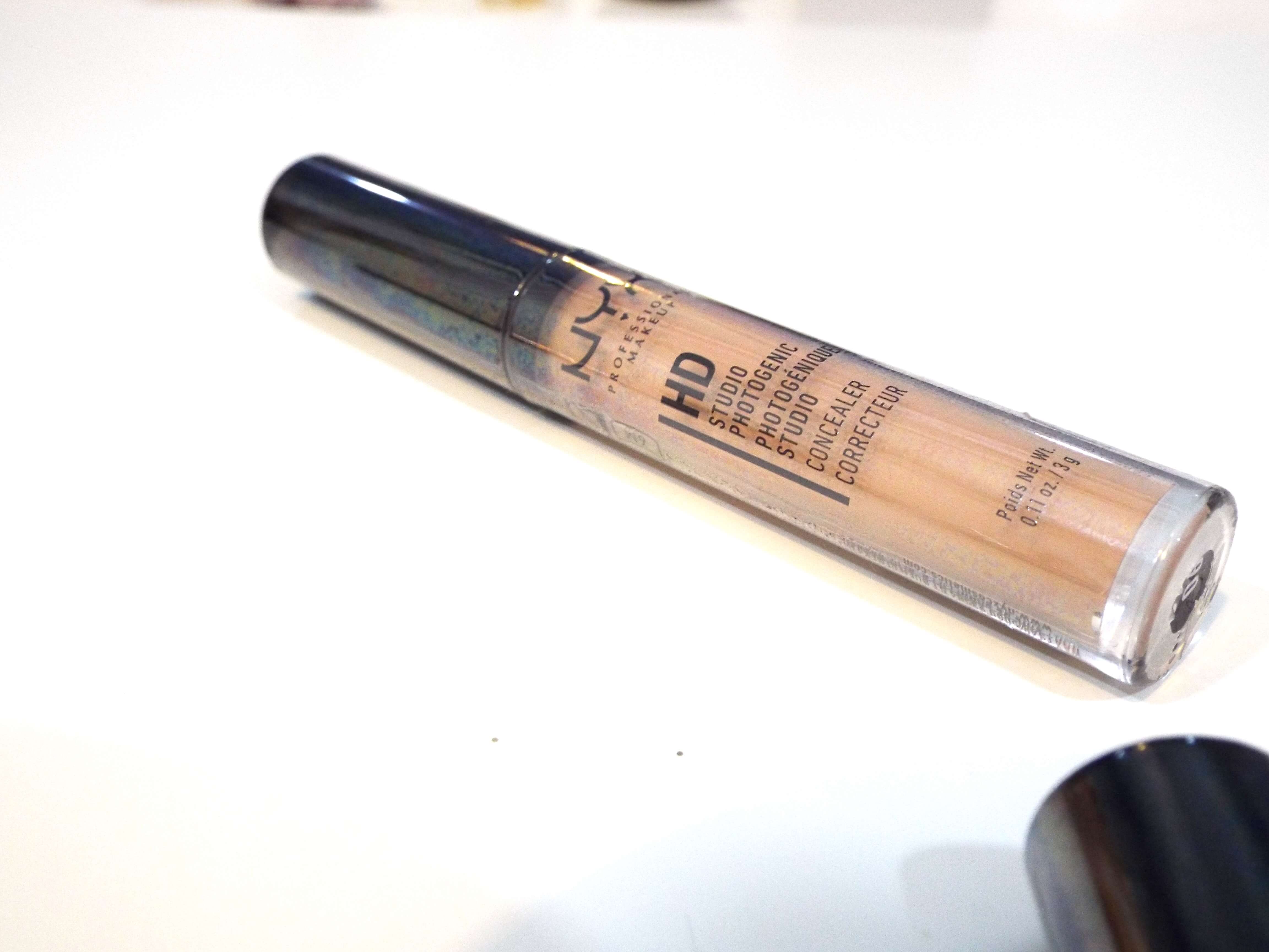 The NYX HD Concealer in shade 06 glow, resting on white desk.