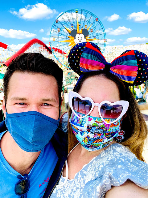 Friends wearing masks and smiling in front of Mickey Fun Wheel at California Adventure.