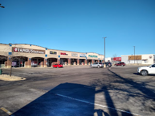 Parking lot with stores and few cars