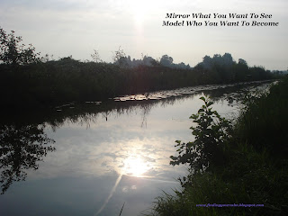 Sun and clouds refelcting in a strip of water surrounded by trees. With wording: Mirror what you want to see, Model who you want to become