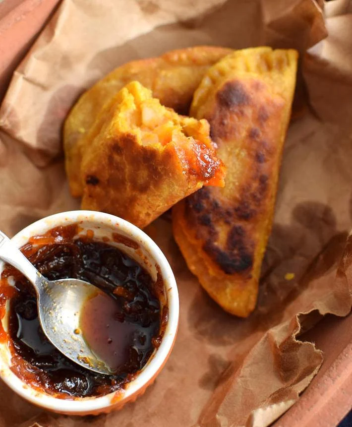 Samosas de vegetales, partida a la mitad y servidas con el chutney de mango