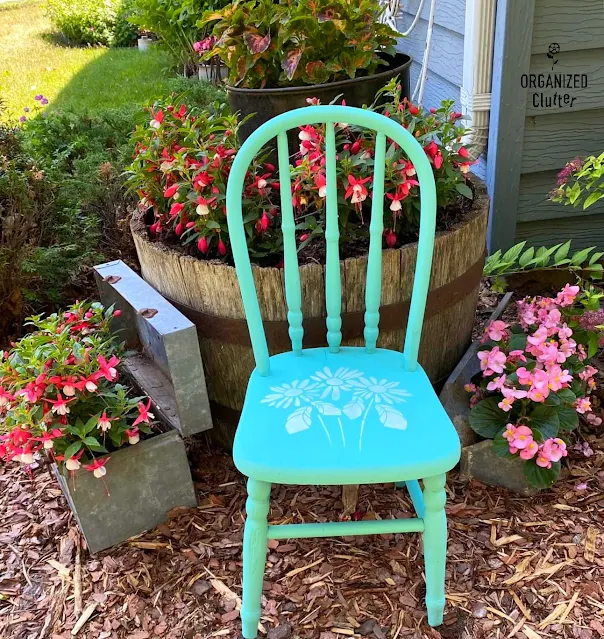 Photo of a wooden child's chair painted turquoise & stenciled with daisies
