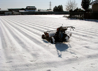 畑にポツンと耕耘機が残された雪の日の写真