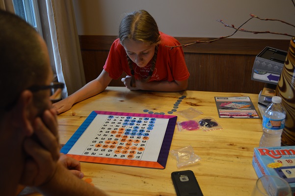 Girl playing a math game with her father at the table