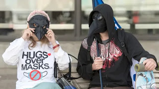 People wear masks during a demonstration opposing the mandatory wearing of face masks and coverings in Montreal earlier this month. (Graham Hughes/The Canadian Press)