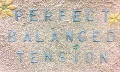 The words Perfect Balanced Tension are quilted on a small quilt
