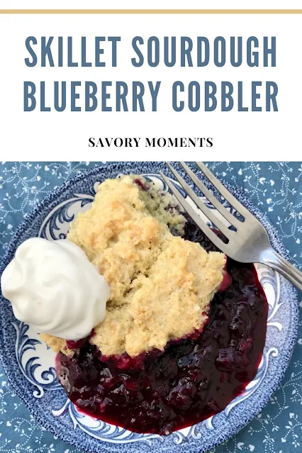 Sourdough blueberry cobbler on a serving plate with whipped cream.