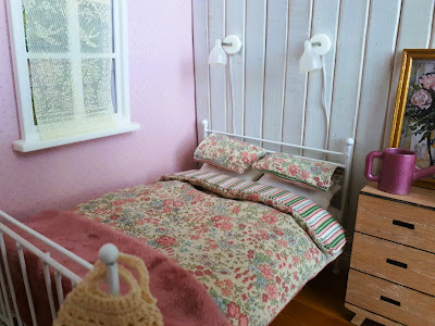 One-twelfth scale modern miniature cottagecore bed with a duvet/doona with small flowers on one side and stripes on the other. There are matching pillowcases.