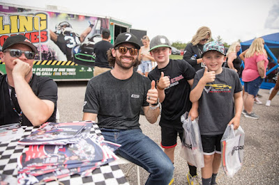 NASCAR Cup Series driver Corey LaJoie gives a thumbs up with two young fans at New Hampshire Motor Speedway in 2022.