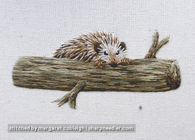 Needlepainted hedgehog climbing over embroidered branch. (Stumpwork and thread painted hedgehog)