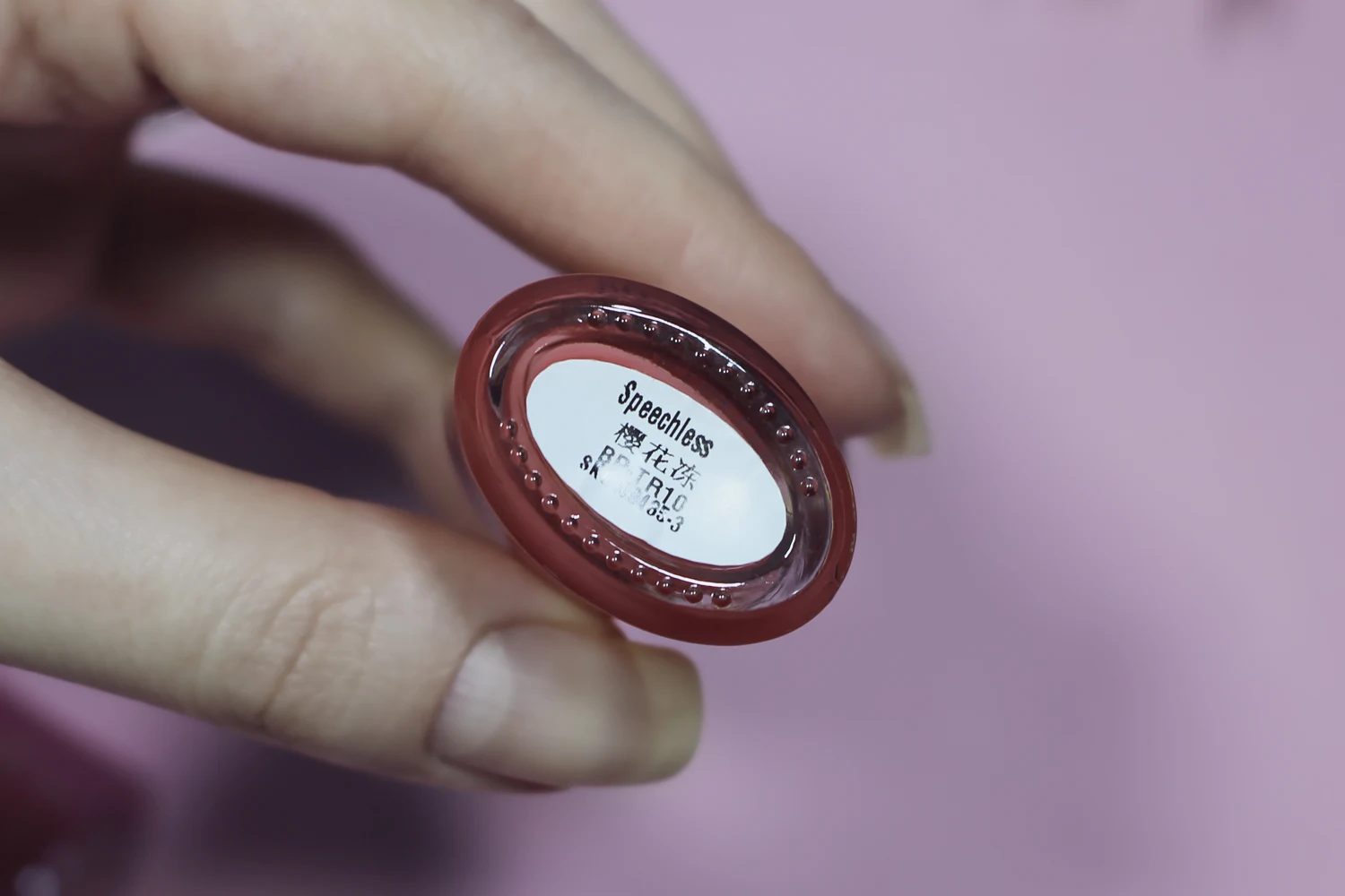 female hand holding a bottle of strawberry nail polish