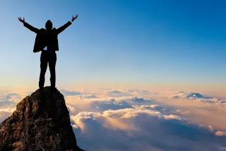 Hombre en la cima de una montaña con brazos abiertos