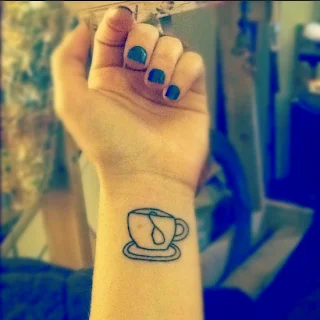 brazo de mujer con tatuaje en la muñeca de taza de cafe