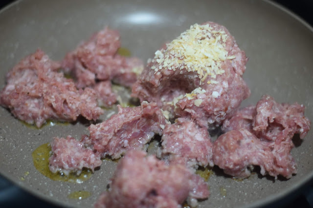 Sausage and dried minced onion browning in a pan. 