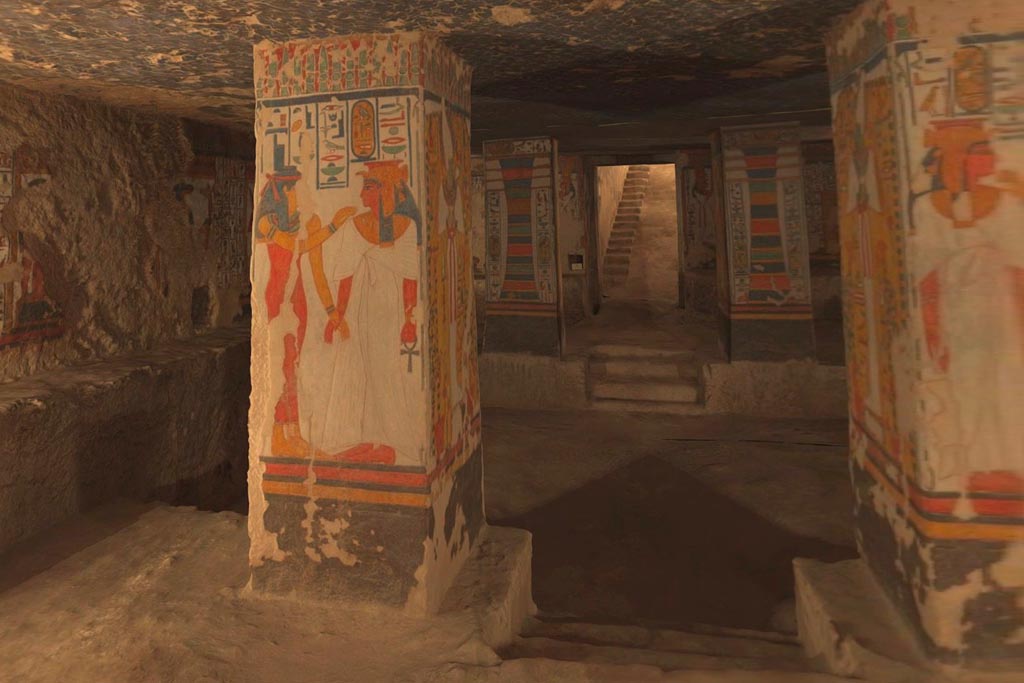 Large room with columns and a rough stone floor. Vivid paintings on the columns.