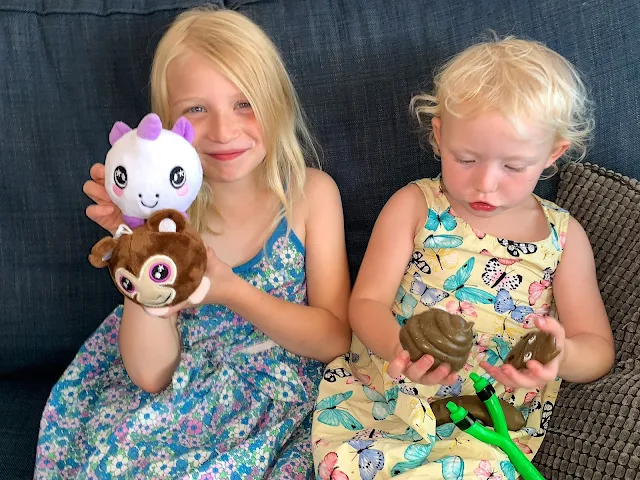 sisters, one playing with squeezy soft toys and the other toy poop