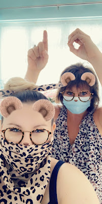 Staff member and service user wearing ppe masks, with support worker signing the number 10 with fingers over service users head.