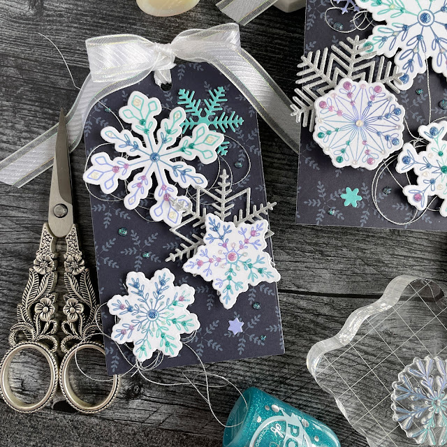 Ombre stamped snowflake tags created with: Scrapbook.com dainty snowflakes stamp and die set, peppermint patterned paper, solar white cardstock, pops of color lavender luster royal blue teal twinkle snowflake, snowflakes die, glitter metals paper; Tim Holtz distress oxide salvaged patina shaded lilac, faded jeans