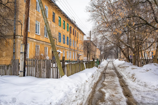 Колея на дороге ранней весной среди жилых зданий