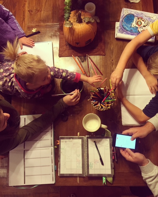 cute family gathered around the table planning out their week Mormon Mom Planner