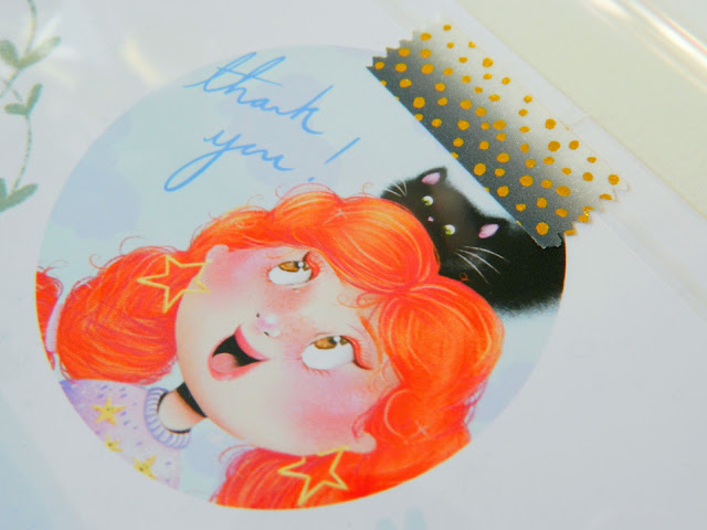 a photo of artwork showing a girl with ginger hair, a happy facial expression and golden star earrings. She had a black cat on her head and next to her, it says thankyou!