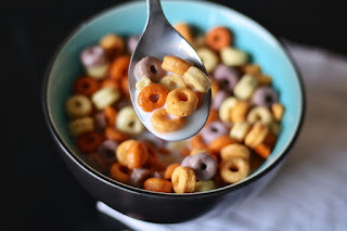 A bowl of multi-colored sweetened cereal with milk and a spoon