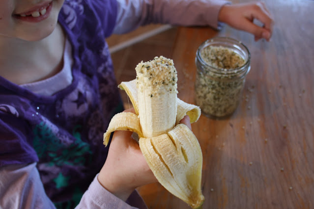 Une enfant tient une banane trempée dans les graines de chanvre