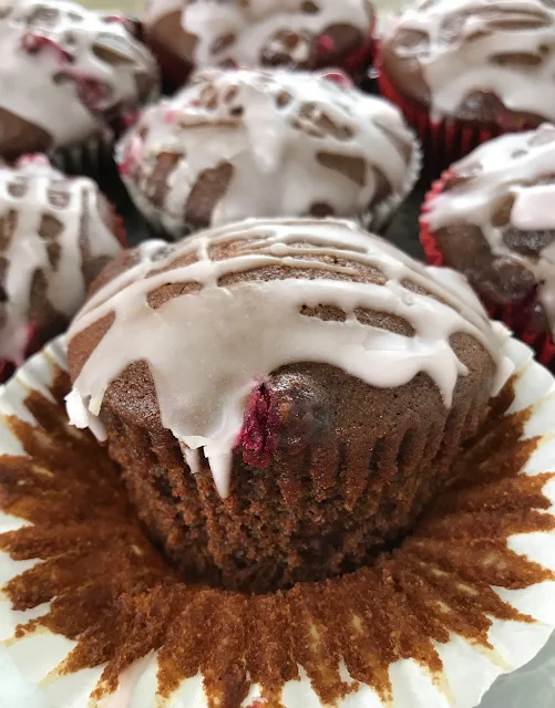 Close-up of one glazed cranberry gingerbread muffin with the muffin paper peeled down.