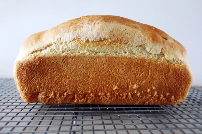 side view of baked buttermilk bread loaf on rack