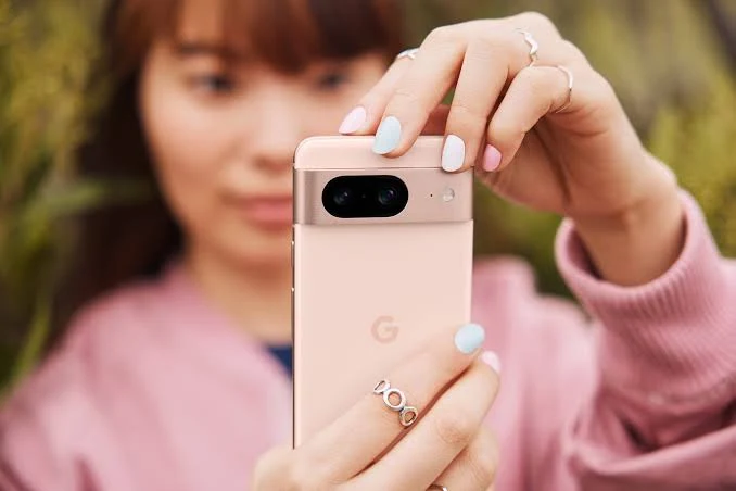 A woman wearing pink sweater taking photo with Google pixel 8