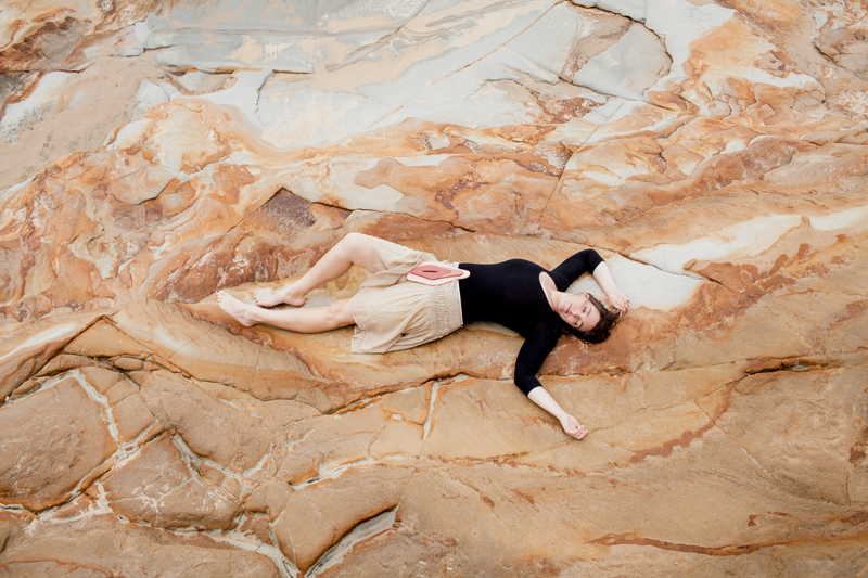 girl lying on rock with wooden vulva