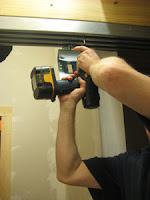 Tom putting a screw in the metal rail with a power drill