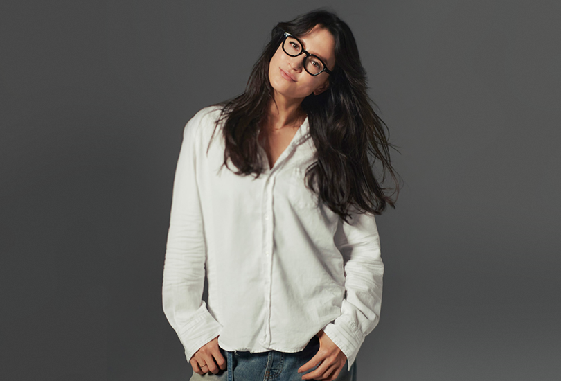 Angela Aki wearing a white shirt and light stone washed jeans, in a promotional shoot for her digital single “Kono Sekai no Achikochi ni”.