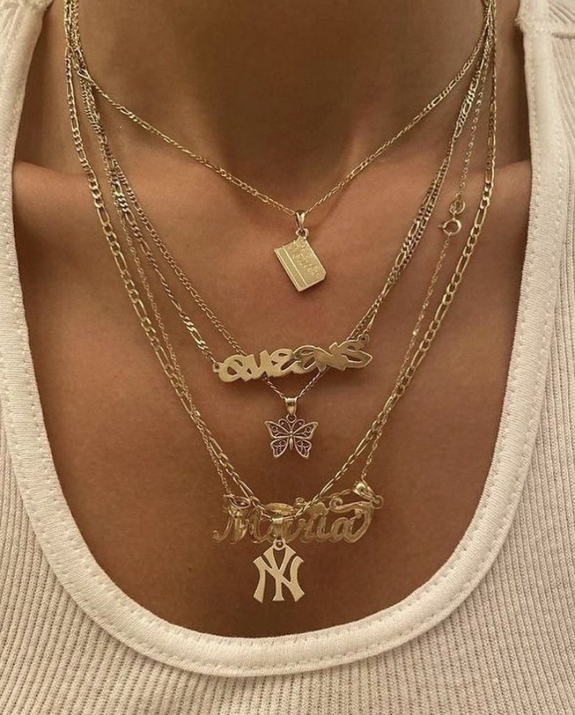 Woman wearing layered gold chains with NY Yankess gold charm and gold name necklace