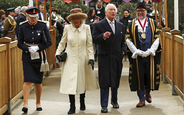 Queen Camilla wore a longline white ivory cashmere cream coat and she paired with a brown wide-brimmed fluffy hat