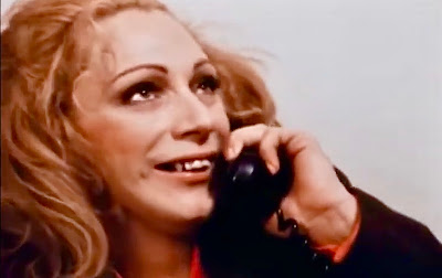 A scene from scarecrow in a garden of cucumbers shows Eve Harrington smiling while chatting on the telephone