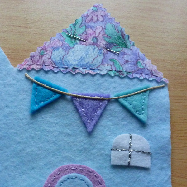 Sewing on twine to bunting garland detail on felt needlecase