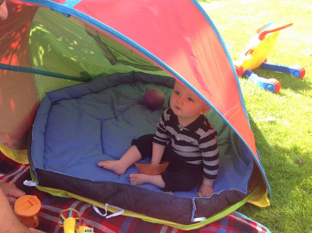 baby in sun tent in garden with orange bowl of food