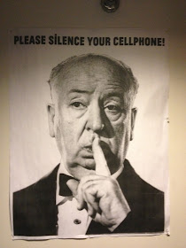 A "please silence your cellphones" poster featuring Alfred Hitchcock from the Brattle Theatre in Harvard Square.